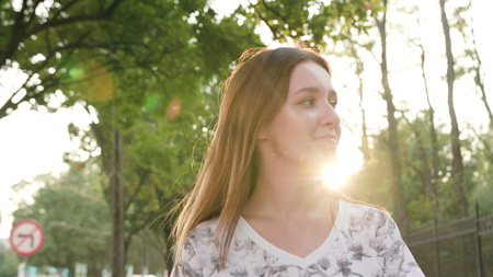An attractive young lady using a phone in town while walking. Close-up dolly shot. Soft focusの写真素材