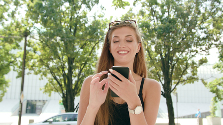 An attractive young lady using a phone in town. Medium shot. Soft focusの写真素材