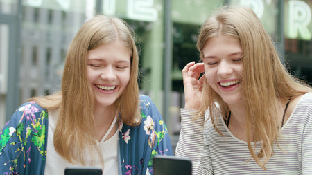 Attractive young ladies using their phones in town. Medium shot. Soft focus