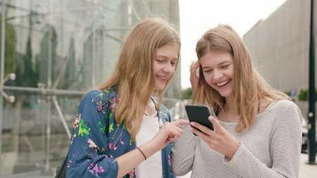 Attractive young ladies using a phone in town. Medium dolly shotの写真素材