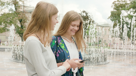 Attractive young ladies using a phone in town. Medium dolly shotの写真素材