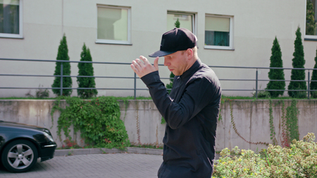 A young man dressed in black breakdancing in the street. Medium shot