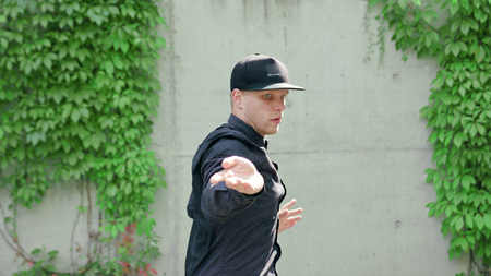 A young man dressed in black breakdancing in the street. Medium shot