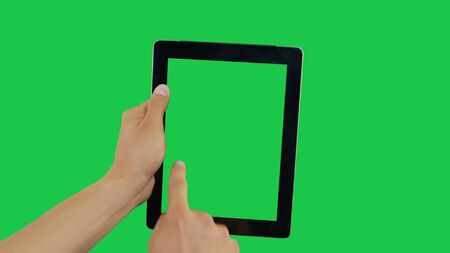 Pointing Finger Clicking On Left Device Screen with Green Background. Digital Tablet Green Screen. Use in any project that depicts finger, gesture, touchscreen and the like.の写真素材
