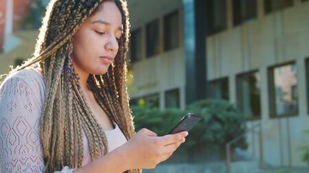 A young lady using a phone outdoors.