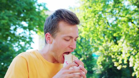 A young man eating outdoors.の写真素材