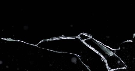 Shattered and broken glass shards flying through the air after crush broken window on a black...