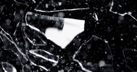 Shattered and broken glass shards flying through the air after crush broken window on a black...