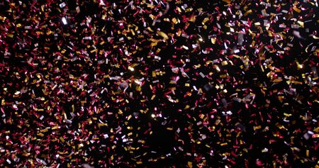 Confetti fired in the air during a party. Only confetti on black background of the night. Falling metallic glitter foil confetti multicolor in black background.の写真素材
