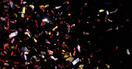 Confetti fired in the air during a party. Only confetti on black background of the night. Falling metallic glitter foil confetti multicolor in black background.の写真素材