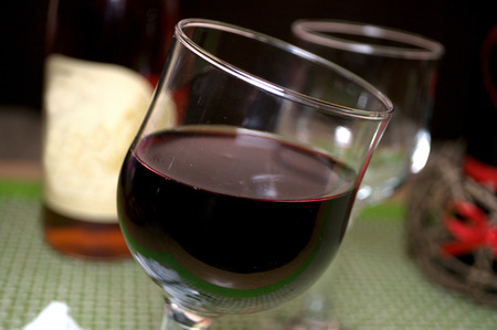 Half full glass of fresh delicious red wine, bottles in the background with heart, Novi Sad, Serbiaの写真素材