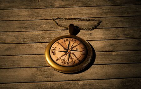 Old gold compass with chain lies on a wooden table. 3d renderedの写真素材