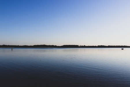 one person stands far from a group of people in the lake. interpersonal relationships cocept.の写真素材