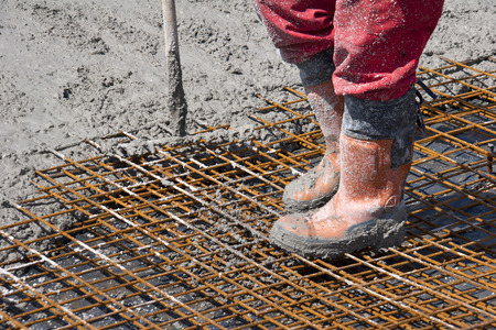 Construction worker spreading freshly poured concrete mix on the bridge