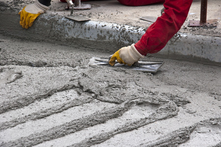 Close up, construction worker spreading concrete with trowelの写真素材