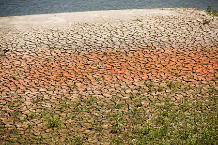 Polluted cracked red land near the riverの写真素材
