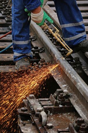 Welder using cutting torch to cut a rail