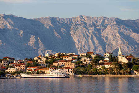 Ferry arrive in picturesque village Sumartin on south-east of Brac island in Croatia, on the background Biokovo mountainの写真素材