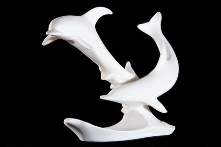 Classic white marble statuette of 2 dolphins isolated on black backgroundの写真素材