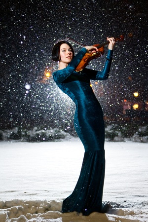 Girl in green dress with violin on snowの写真素材