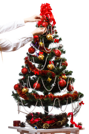 Decorating christmas tree with balls, ribbons and stuff, isolated on white backgroundの写真素材