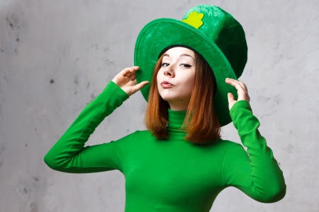 Red hair girl in Saint Patrick s day hat isolated on grey grunge backgroundの写真素材