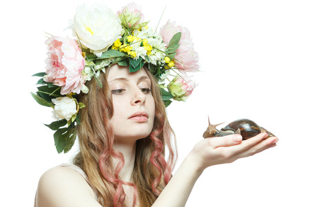 pretty girl with snail in hand and flower crown on head isolated in white backgroundの写真素材