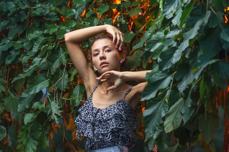 Fashion portrait shoot of a beautiful teen girl during city fashion photoshoot with greenery at backgroundの写真素材