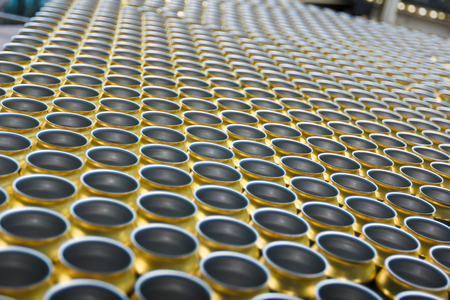Empty golden beverage cans on the conveyor beltの写真素材