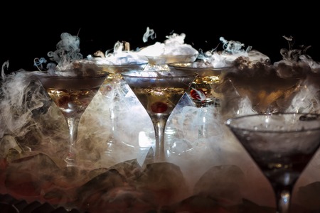 drink in glasses with the effect of dry ice on black backgroundの写真素材