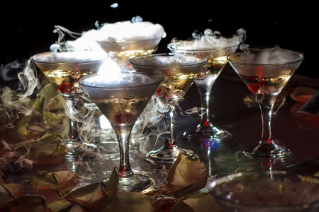 drink in glasses with the effect of dry ice on black backgroundの写真素材