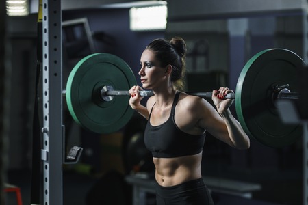 Concept: power, strength, healthy lifestyle, sport. Powerful attractive muscular woman CrossFit trainer do workout with barbell at the gymの写真素材