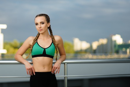 Concept: healthy lifestyle, sport. Attractive happy girl fitness trainer do outdoor workout at modern downtown urban area during sunset.の写真素材