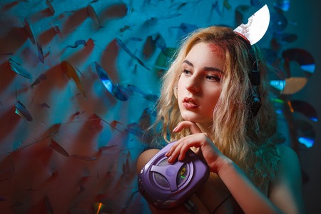 Concept: deadly music, sound kills. Beautiful young woman in headphones with bloody parts of cd sticking out of her head. Accident murder victim. Undead.の写真素材