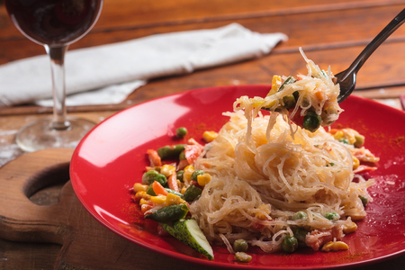 Concept: restaurant menus, healthy eating, homemade, gourmands, gluttony. Rice noodles with green beans and vegetables on a messy weathered wooden background.の写真素材