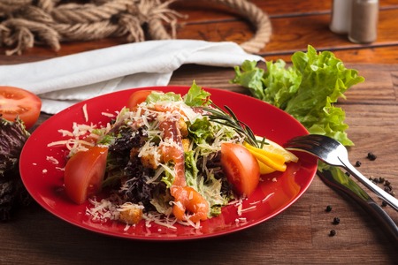 Concept: restaurant menus, healthy eating, homemade, gourmands, gluttony. Caesar salad with salmon and cherry tomatoes on a weathered wooden background.の写真素材