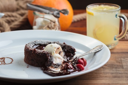 Concept: restaurant menus, healthy eating, homemade, gourmands, gluttony. White plate with chocolate fondant with strawberry and ice cream on a messy vintage wooden background.の写真素材