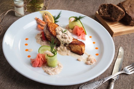 Concept: restaurant menus, healthy eating, homemade, gourmands, gluttony. Grilled salmon with shrimp and cream sauce with ingredients and vintage cutlery on sackcloth background.の写真素材