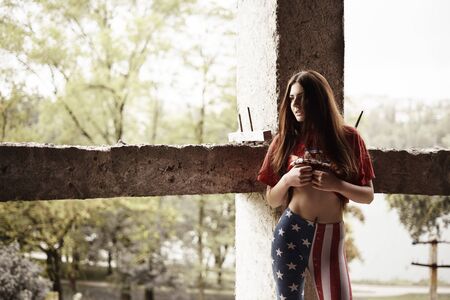 Concept: gritty, millennial. Gorgeous beautiful young girl wearing USA themed clothes photoshoot in abandoned construction of building presenting the contrast of fashion and grunge.の写真素材