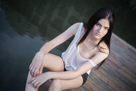 Concept: gritty, millennial. Gorgeous beautiful young woman photoshoot in abandoned urban location near water pier presenting the contrast of fashion and grunge.の写真素材