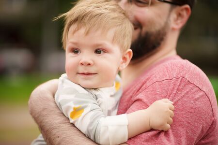 Concept: family values. Close-up portrait of adorable innocent funny brown-eyed baby smiling with his hipster father.の写真素材