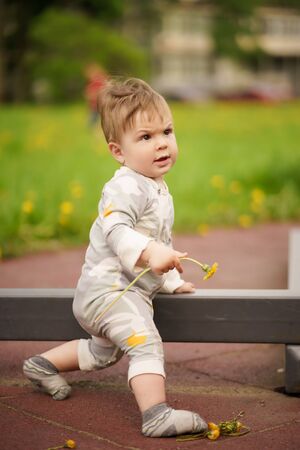 Concept: family values. Portrait of adorable innocent funny brown-eyed baby playing at outdoor playground with serious face.の写真素材