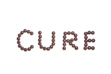 Cure written with brown pills - white backgroundの写真素材
