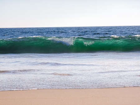 Rising wave reflecting sunlight through it and showing beautiful colorsの写真素材