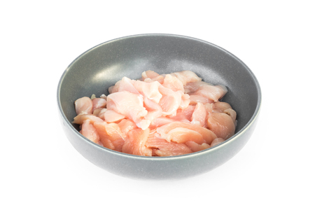 Pieces of raw chicken fillet in bowl on white background, raw material for cookingの写真素材