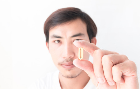 Closeup man hand holding fish oil medicine with white backgroundの写真素材