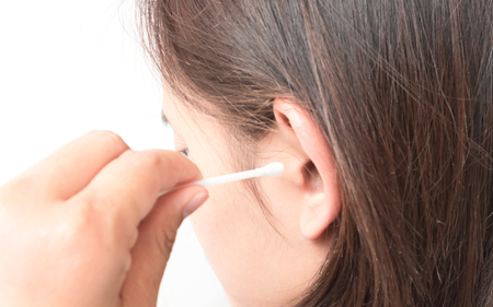 Closeup woman cleaning ear with cotton bud, health care concept, selective focusの写真素材