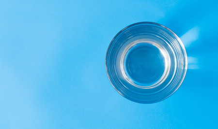 Closeup top view water in glass on blue backgroundの写真素材