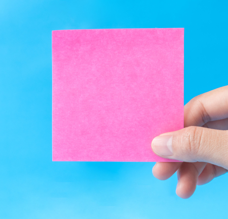 woman hand holding pink paper on blue backgroundの写真素材