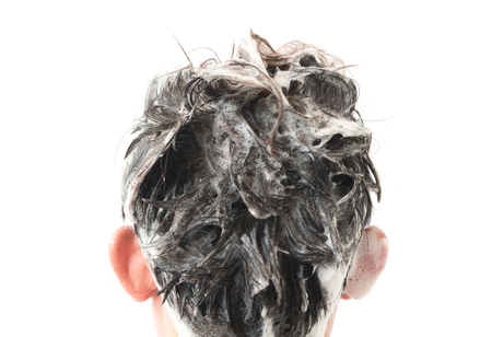 Closeup young man washing hair with white background, health care conceptの写真素材